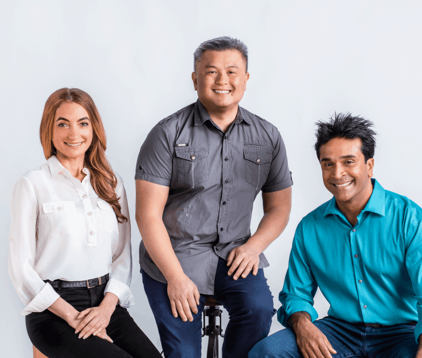 two men and one woman are sitting and posing for the camera | OrthoFx