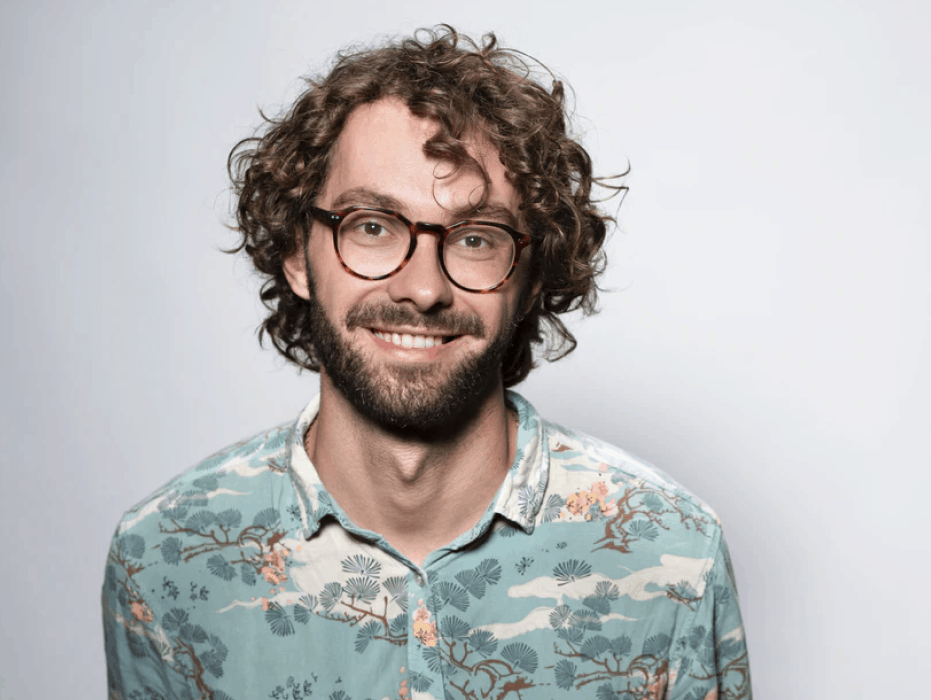 Man smiling with curly hair wearing specs | OrthoFx